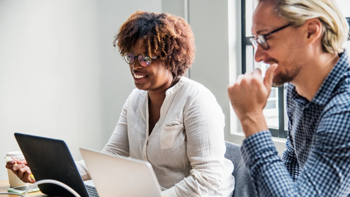 Female and male co-workers collaborating beside each other on laptops